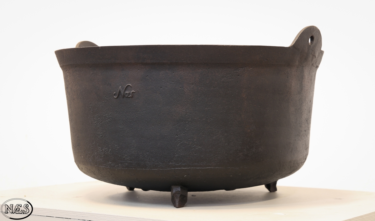 Rund jerngryte med tre bein og to ører på øvre kant for feste av hank.