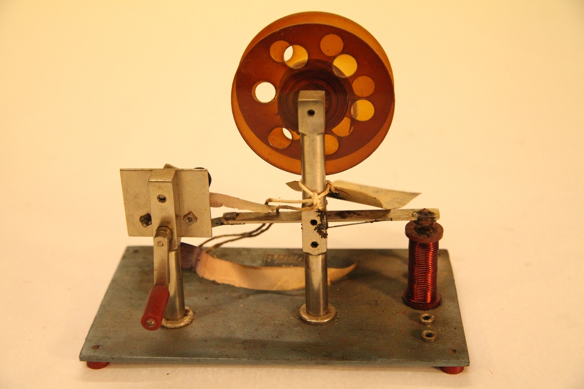 Morseapparat med sender og mottaker. Mottakeren har rull med blåpapir som setter merker ved hvert tegn. Må sveives manuelt.