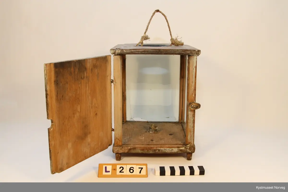 Lykt i tre med glassvegger og tredør. Lykta er rektangulær, og har tre vegger av glass og tredør. I bunnplata er det innfelt et metallfeste for talglyset. I toppen er det laget åpning for varme og røyk fra lyset. I tillegg er det laget to hull i lokket for feste av tauhåndtak. Hjørnene har trestykker, hvor det er laget spor for innsetting av glasset. Likeså topp og bunnplate. Døra låses av med en lite trestykke som kan vrides.