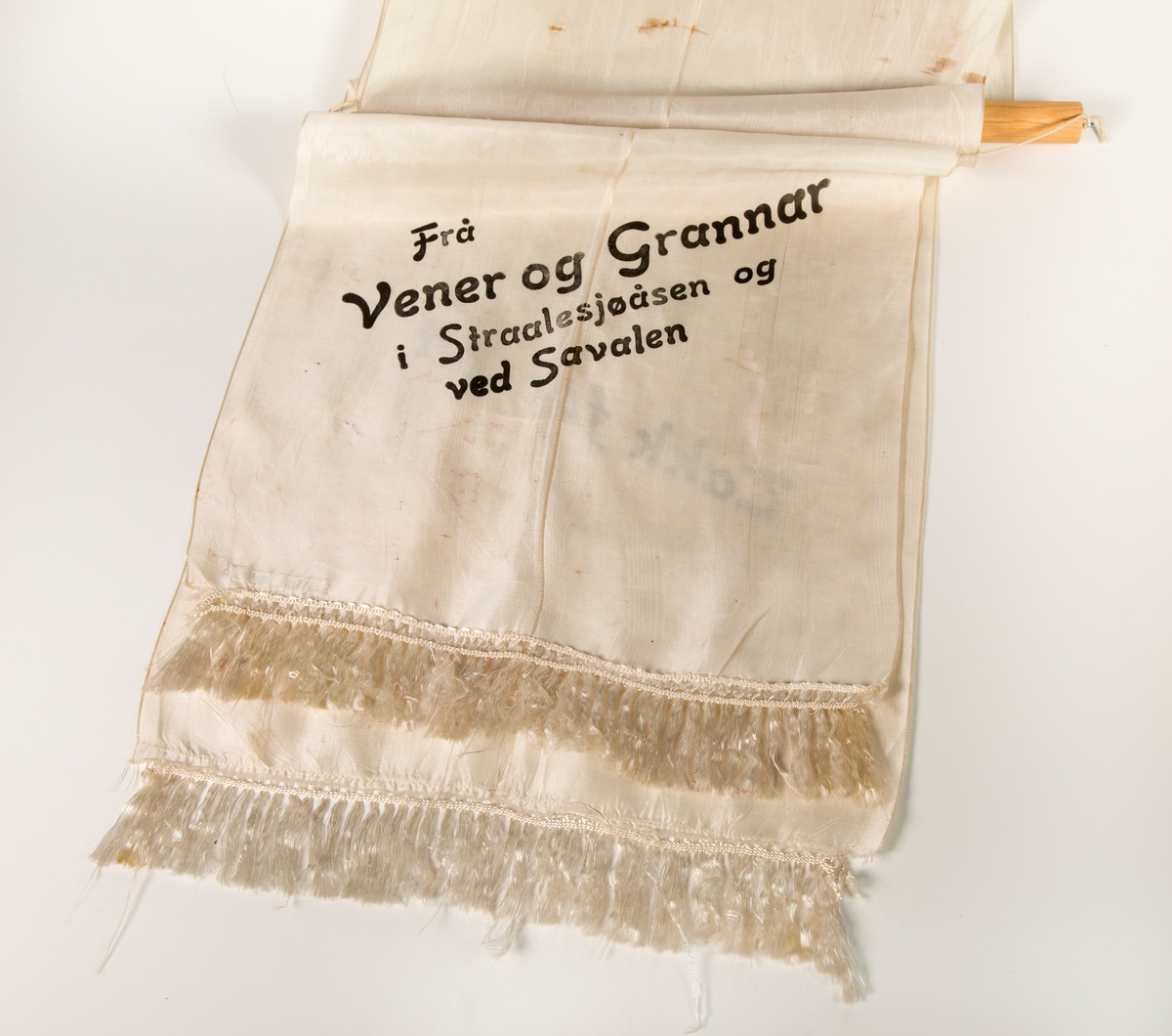 Stort sørgebånd til begravelse. Festet til rundstokk for oppheng på vegg. Til Garborgs begravelse.