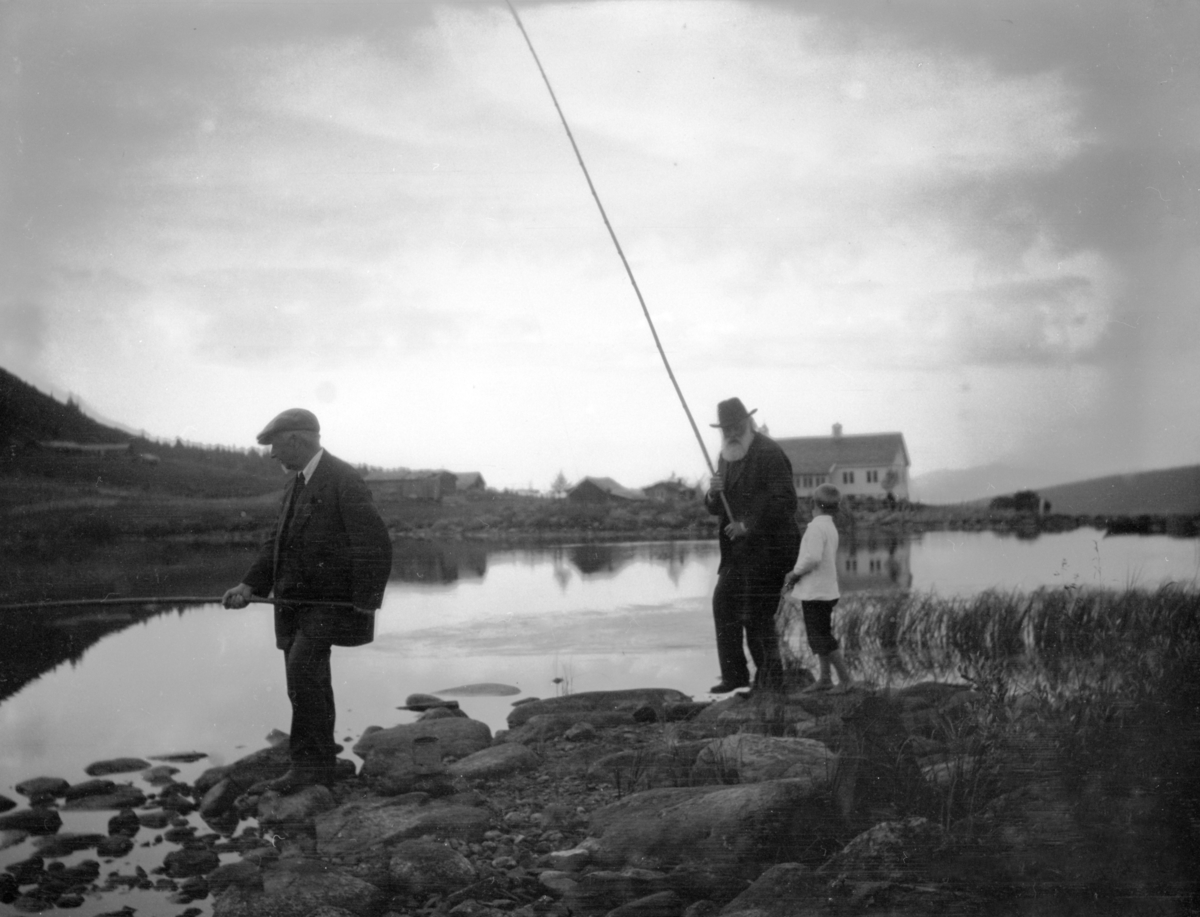2 menn og et barn fisker i fjellvann mulig i fjellet ved  Fron.
Johan Kjorstad med fiskestang. Mulig professor Torstad til v.