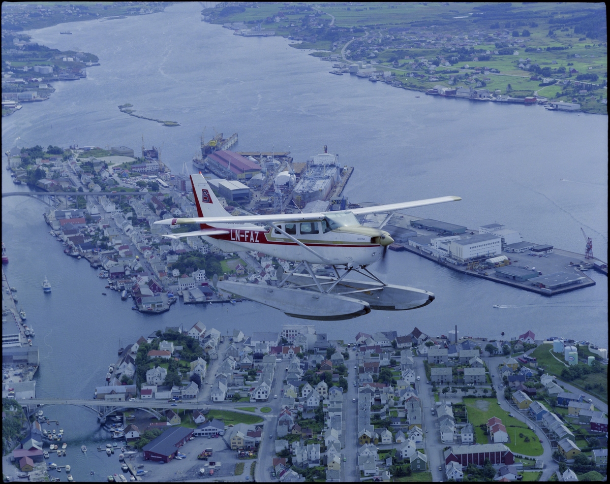Et sjøfly fra "Coast Aero Center" flyr over byøyene Bakerøy og Risøy i Haugesund. Det står "LN-FAZ" på siden av flyet. Bildet er tatt fra fly.