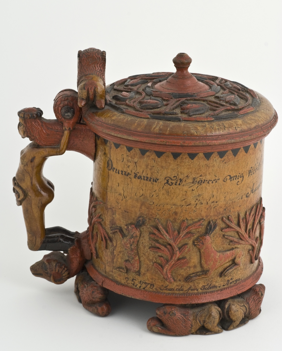 Dekorert med fortløpende billedfrise med dyr og trær på nederste del av korpus. Kannen har løveføtter og løvegjekk og bakkantine som håndtak. 