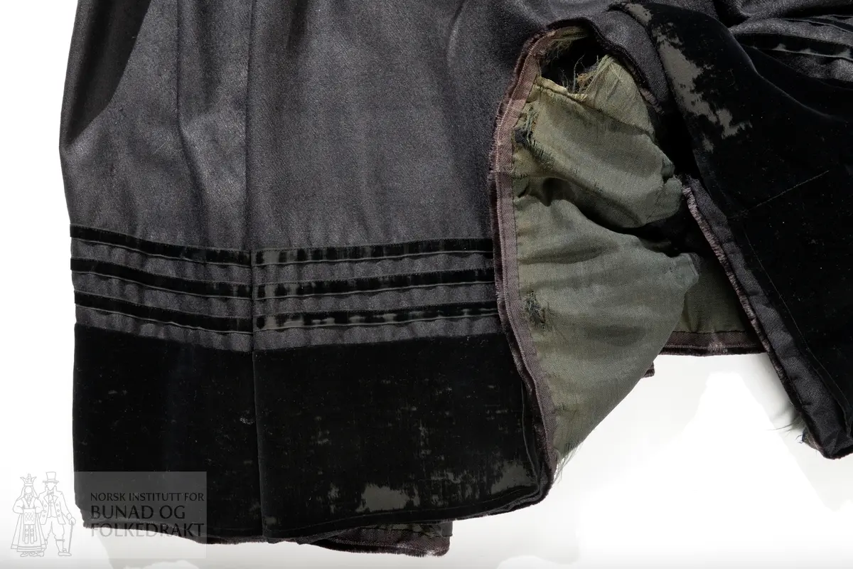 Liv sauma av raud ullkypert, lett valka. Fora med ubleika bomullslerret.
Ermhole, rundt hals og opning framme er kanta med blomstermønstra fleirfarga fløyelsband med svært avslitt fløyel. Innanfor kantingar er det påsett eit smalt metallband.
Etter framkantane er det påsett 3 borer på kvar side, dei to øverste litt breiare enn dei fire nederste, alle har eit skåleforma lauv festa i midten. På framsida av den kurva delen er det fem ulike stempel: 63 i eit sirkelforma stempel, truleg årstalsstempel. Månadsstempel: 6 over M i rektangelforma stempel. Mesterstempel i bølgeforma ramme LAR, Lorentz Christopher Angel Reimers, fekk borgarskap i Bergen i 1832. Lødighetsstempel 13 1/3. Trapesforma stempel med 7 prikkar, Bergens bystempel.
Lukking framme med to metallhekter på kvar side.
Heile livet er sauma på maskin. Kanting er sauma for hand. 
Livet sauma på stakken for hand. 
Stakken er av heimevove ullerret, blåsvart. Splittopning midt framme. Samansett av 5 rette høgder med jare i begge sider, alle høgder. Faldelagt oppe med eit glatt felt framme mot splitt. Høgdene er sauma saman med maskin. 
Nedkant: 3 svarte smale sillkefløyelsband, nedanfor dei eit påsett stoffstykke av svart bomullsfløyel. Dette stoffet er ein hengefald, ikkje sauma fast i nedkant.
Nedkanten er skonna på innsida med eit lerretsvove mohairstoff av mørk grøn farge. Sauma på med maskin. I nedkant av skonninga er det påsett eit blåsvart kosteband sauma på for hand.
Kanten på linninga er av svart bomullssateng. Er bretta dobbelt og sauma på for hand på begge sider