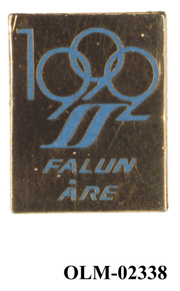Rektangulært merke med tekst i blått og emblemet for søkerbyen Falun 1992.