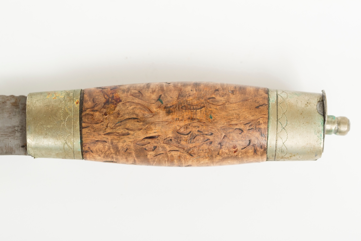 Tollekniv av tradisjonell norsk/nordisk type. Håndsmidd laminert blad med nedsvingt spiss og to dekorhakk innerst på ryggen. Store bruksspor med slagmerker på rygg og hakk i bladet. Store rustpartier. Gjennomgående ulimt tange med tapp til slirestropp. Skaft i valbjørk. Håndlagde loddede holker, mest sansynlig av nysølv (legering av messing, kobber og zink), med trambulerte dekorborder. Bladholken er løs. På toppholken har loddingen løsnet helt slik at toppen er totalt adskilt fra sidedelen av holken. 

Bladet er stemplet L.S. I følge Norsk knivforening kan dette være
Skålbø, Lars Sondresen 1850-1940, NO-01547, Tinn / Telemark
Kategori: Smed, Kjennetegn: Stemplet  LS (skjønnskrift), LS og L.S. TINN. på knivbladene.