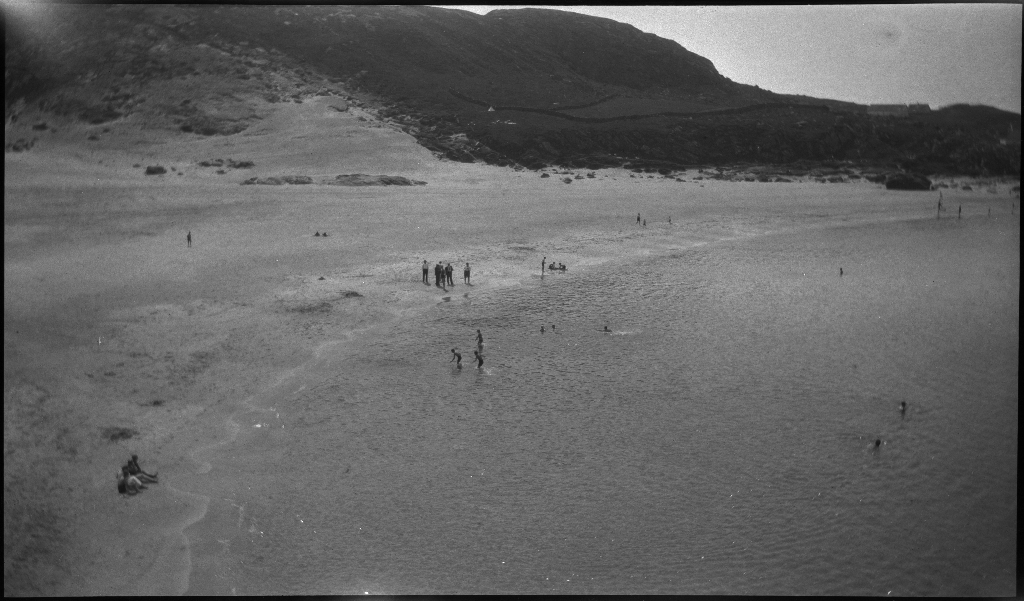 Barn og unge på og rundt stranda i Vigdelsvika. De fleste har satt opp telt, noen soler seg og noen bader. Den ene gutten på bilde nr. 6 holder et flytebelte.