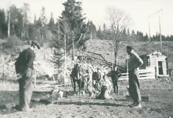 Flere mennesker jobber ute på et jorde, en guttunge holder e