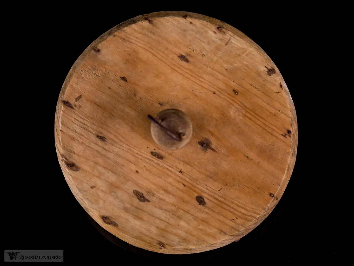 Sirkulær treplate med en dreid trehåndtak med metallhempe. Flere metallkroker er festet på undersiden for festing av lysveker.