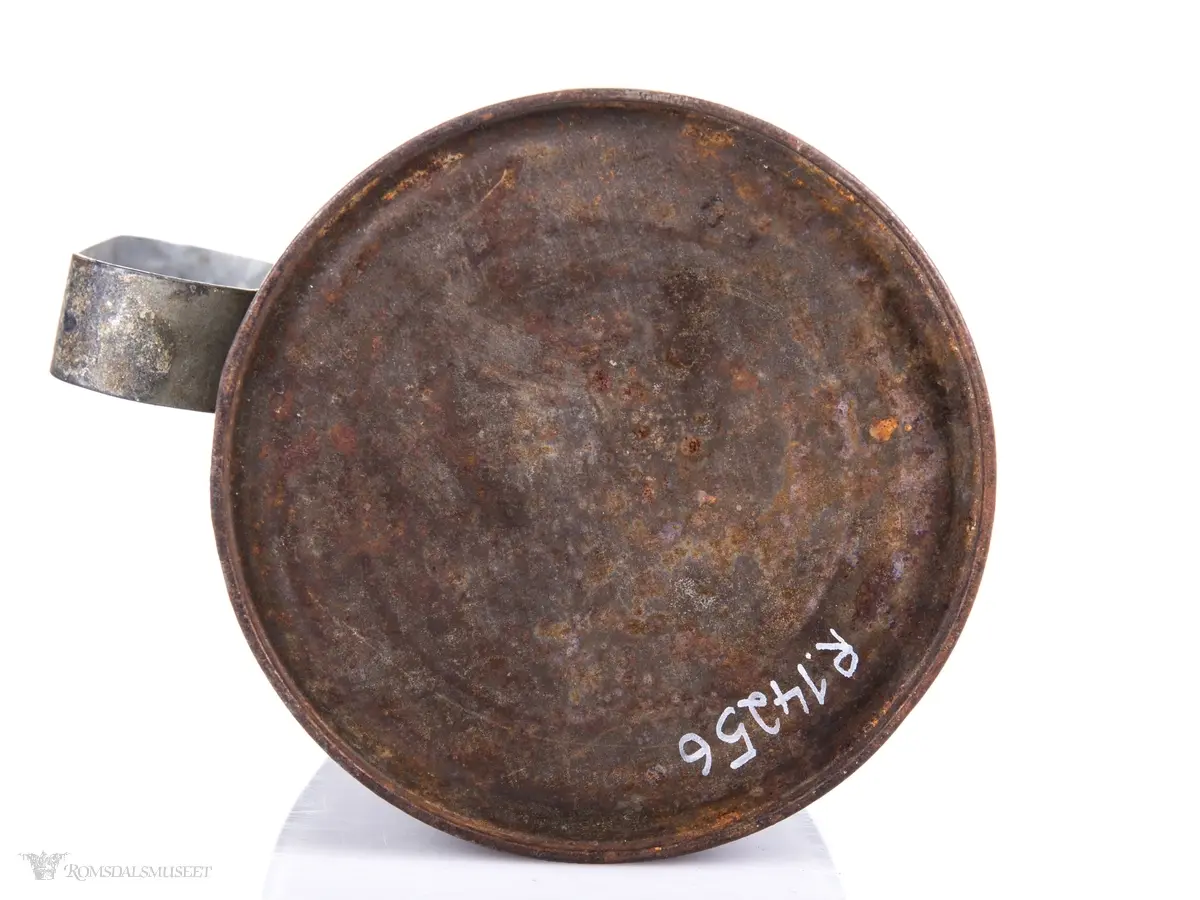 Sylinderformet blikkboks som kropp, med påloddet buehåndtak og en skråstilt plate med tenner foran.