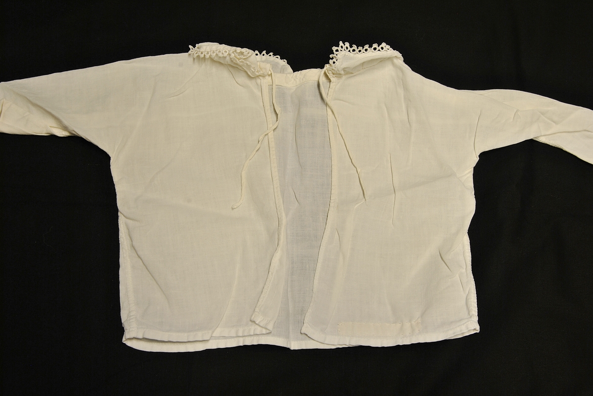 Rektangulær form. Knytinger bak. Nuppereller på krage og ermene.