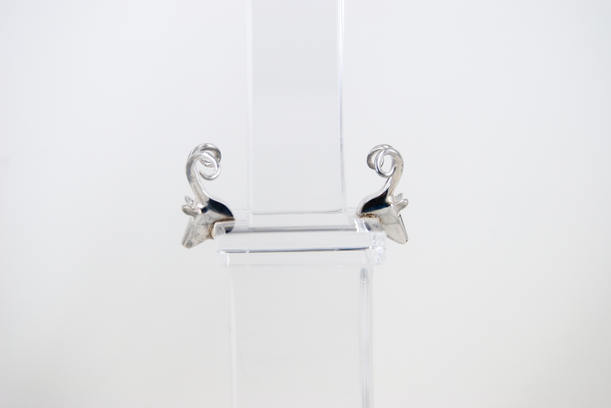 Ljusstakar, par, av kristall och silver, modell "Rosendal". Design Gunnar Cyrén, tillverkning Orrefors. På låg, kvadratisk fot ett rakt, fyrsidigt skaft, avdelat i en lägre bredare och en högre smalare del. Allt i kristall. Överst ljuspipa i silver, formad som svagt konvex vas, indelad i 12 vertikala segment. Monterat på motstående sidor i höjd med avsatsen två hjorthuvuden i silver. Graverat i kristallen: "Cyren och Orrefors Gallery -92 986972 Gunnar Cyrén 10-10". Röd, sköldformad etikett med orre och texten: "Orrefors Sweden". 6 st silverstämplar.