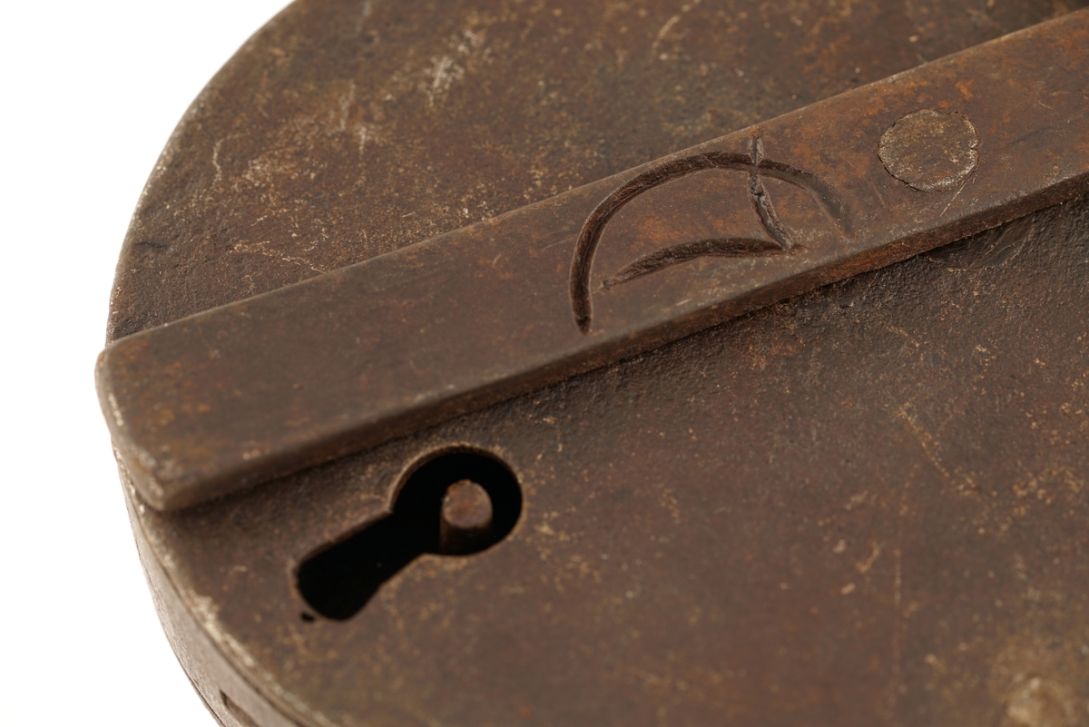 Hengelås, oval, av jern, med svingbart lokk over nøkkelhull. På det svingbare lokket er det inngravert; C 7.
Nøkkelen har firkantet skjegg og er blank.