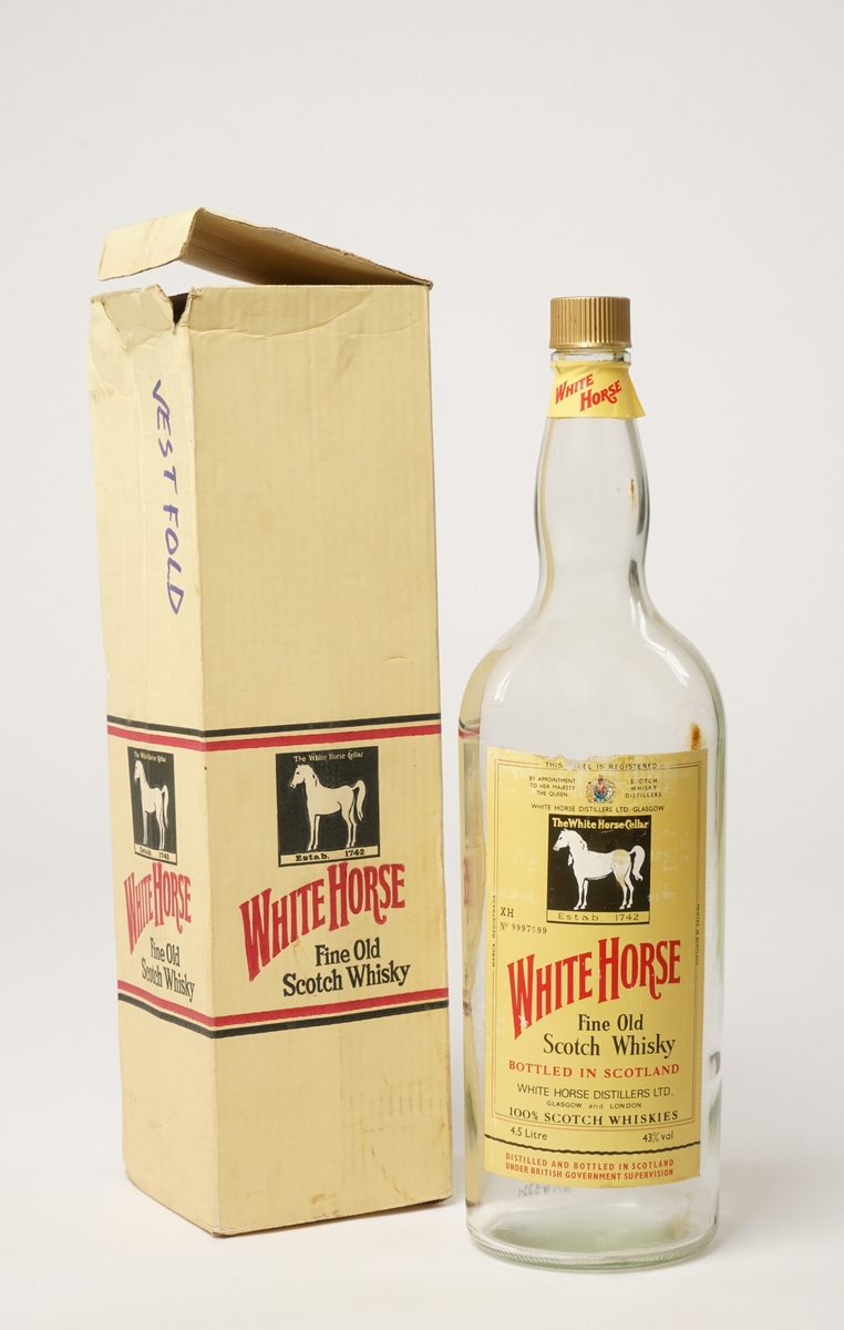 En flaske på 4,5 l whisky. White Horse fine old scotch whisky. Original papp-emballasje er intakt. Skrukork,
som er gullfarget.