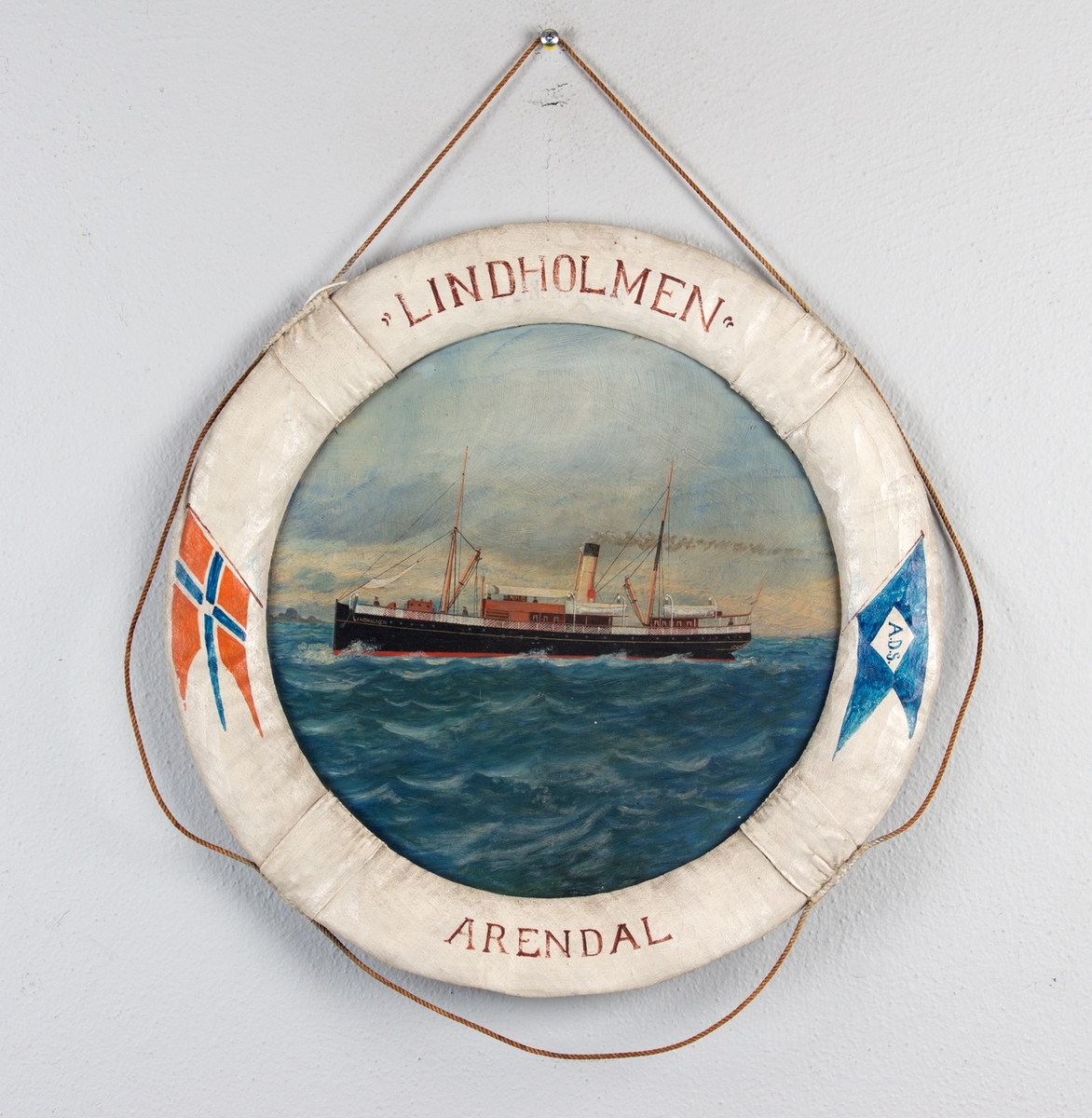 Skipsportrett av DS LINDHOLM i rom sjø. Rammen er utformet som en livbøye dekorert med norske flagg og skipets  navn og hjemmehavn.