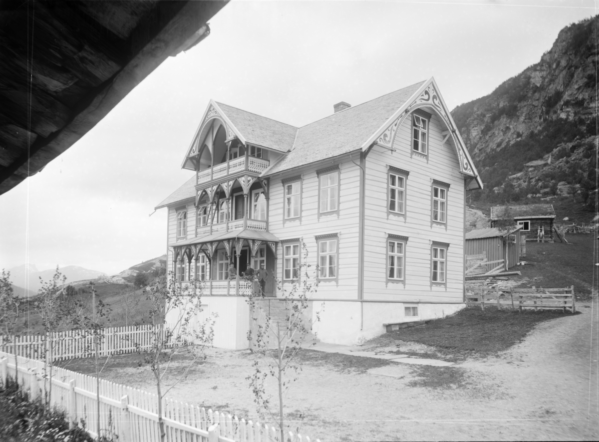 Stueflotten hotell. 2 menn med hatt og en med uniform i inngangspartiet tatt mot Romsdalen. I bakgrunnen Døntind og Sæterhø.