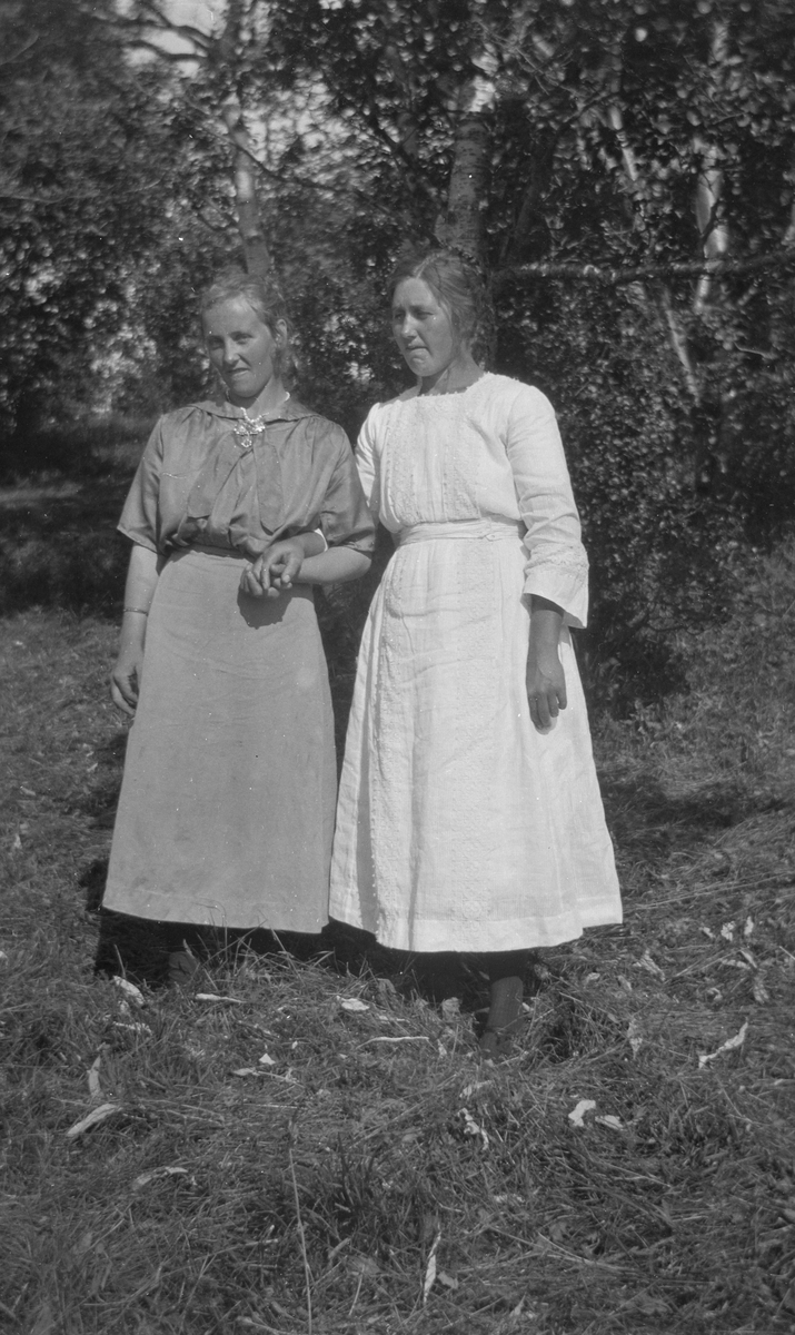 To kvinner står hånd i hånd.