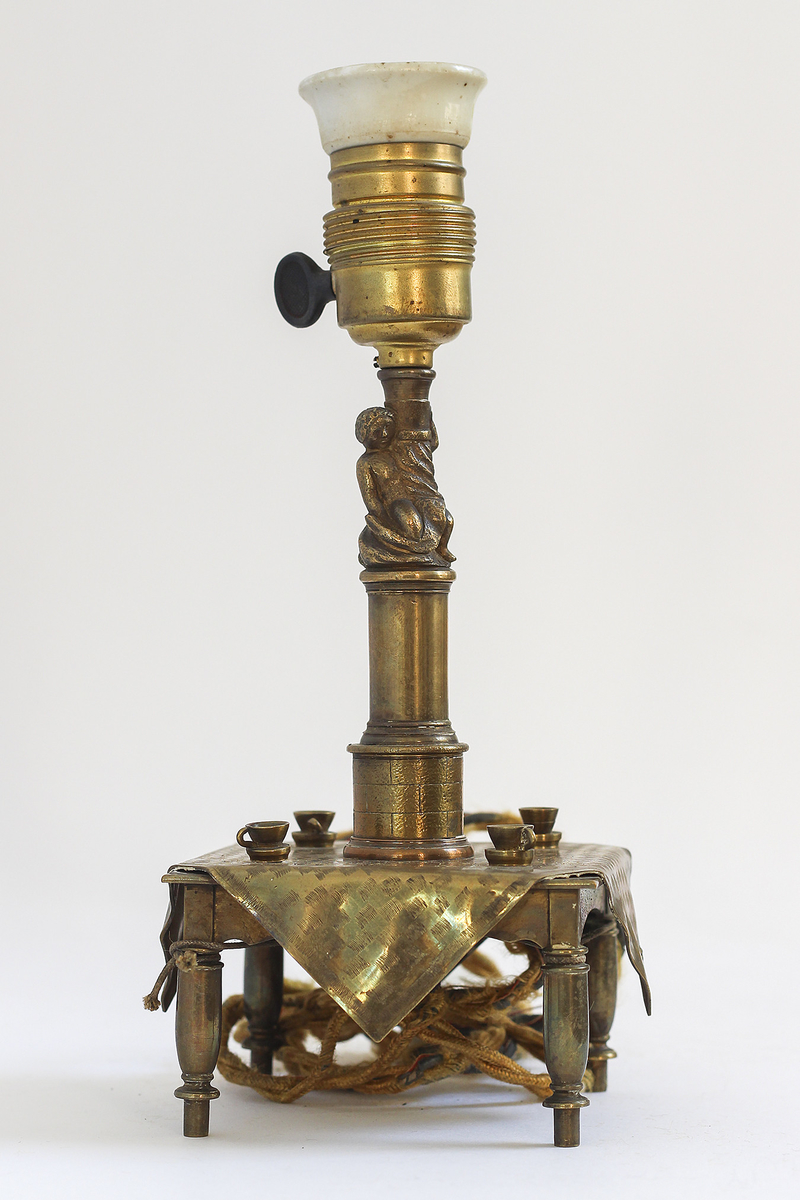 Lampefot i messing utformet som et kvadratisk bord med duk og kaffekopper.
