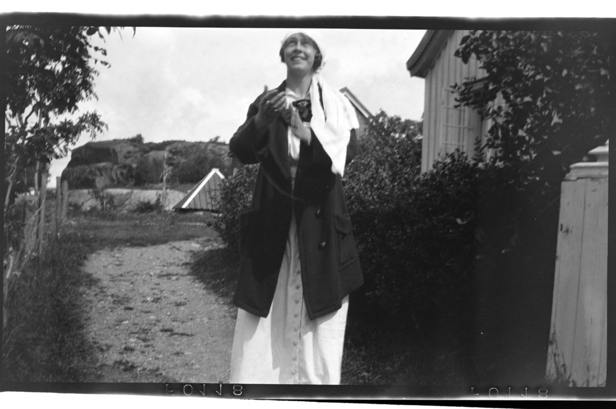 Birgit Aubert står på et gårdstun, Hvasser. Fotografert 1917.