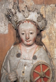 Ett helgonskåp med en kvinnofigur föreställande Sankta Katarina. I sin vänstra hand håller hon sitt attribut, ett hjul. På huvudet bär hon en stor krona med blad och applicerade rosetter i trä längs kanten. Katarina bär en förgylld dräkt och mantel med blått foder. Hjulet är gult med en röd bakgrund mellan ekrarna. Skåpet har snedställda sidor på ett rektangulärt bakstycke. Sockelns framsidor har masverk.