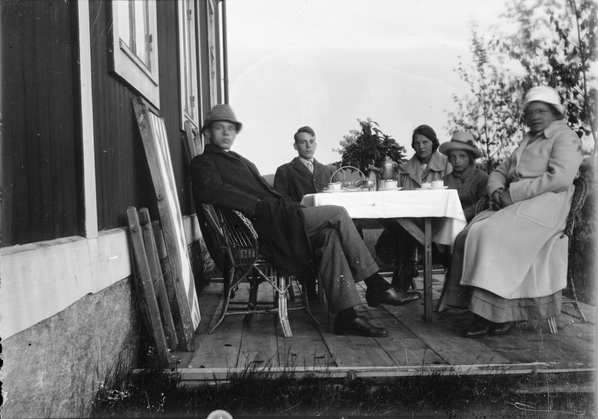 Roland, Alf, Ingemar, Marit och Christiane Liljefors, samt en annan kvinna, har en kafferast ute på altanen, sannolikt på Svensgården, i Leksand, Sverige