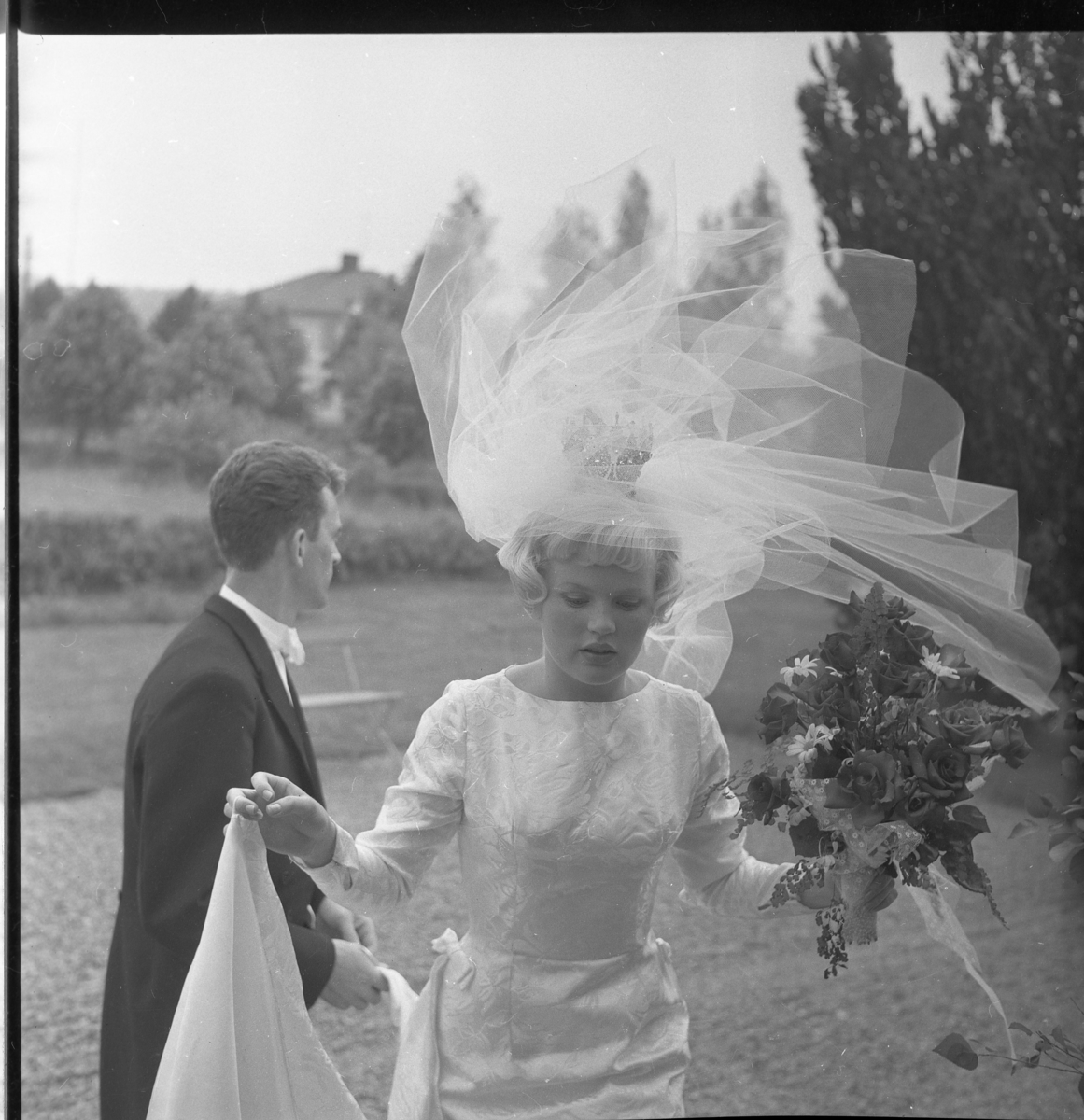 Nygifta Lisbeth Johansson och Rolf Nilsson utanför Örserums kyrka. Hon håller släpet i sin hand och vinden drar i brudslöjan.