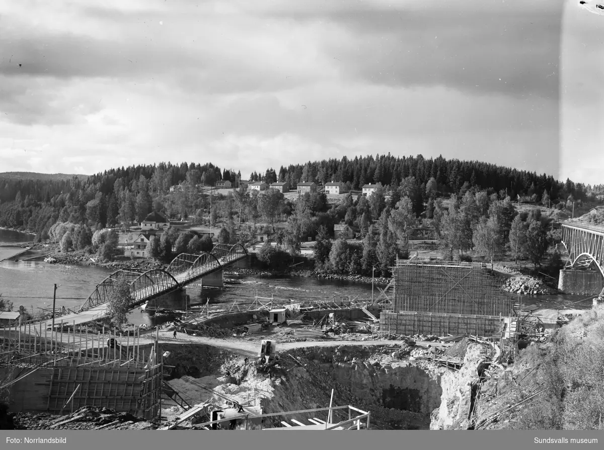 Kraftverksbygget i Bergeforsen framskrider. Vyer, bergsprängare, svetsare och administrativ personal. På första bilden syns den gamla landsvägsbron till vänster samt järnvägsbron i högerkanten av bilden.