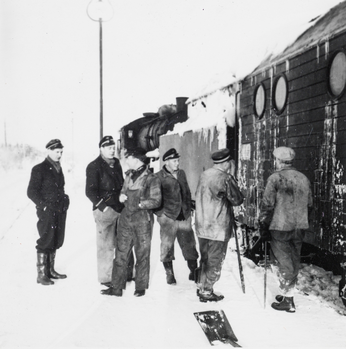 Jernbanepersonale foran snøryddingstog på Nordlandsbanen. Nærmest roterende snøplog type III, bak damplokomotiv type 33c nr. 396.