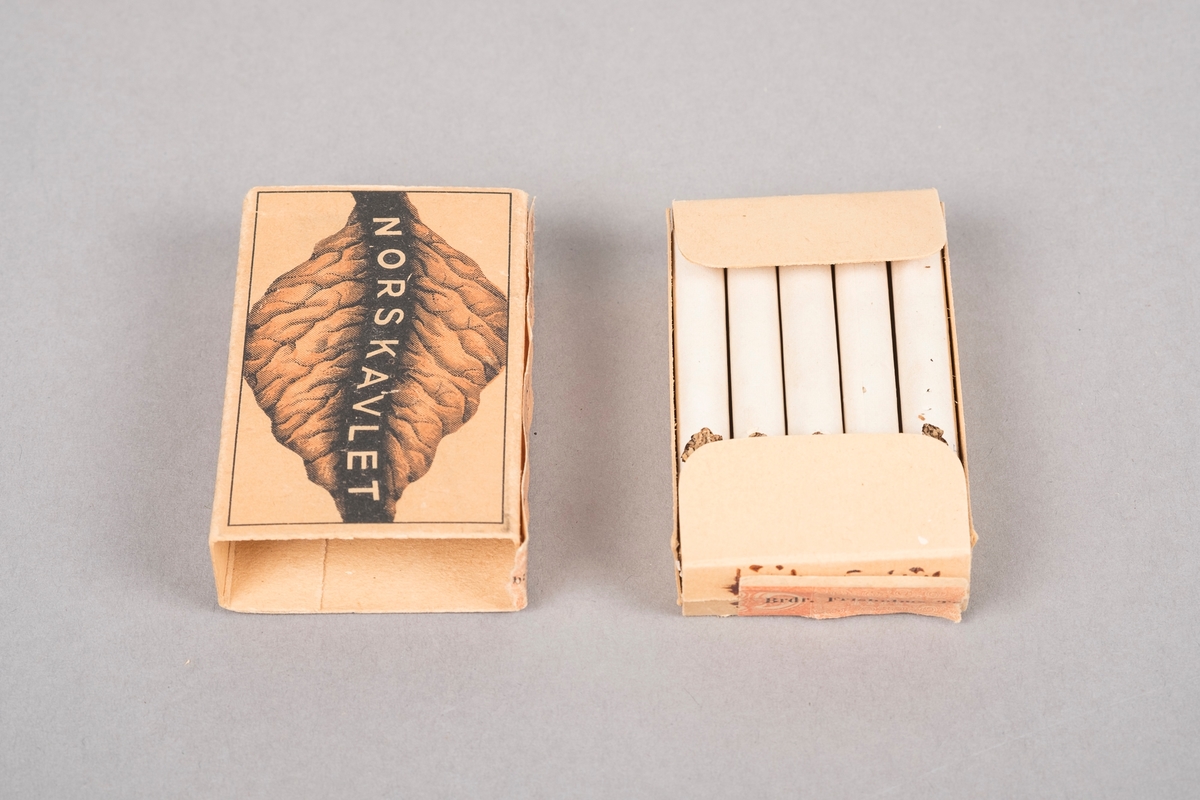 Fire tobakksblader, to og to sammen. Fabrikklogo mellom tobakksbladene. F'en i logoen er tegnet som en pipe og en sigarett. Forsiden av esken har motiv av et tobakksblad.