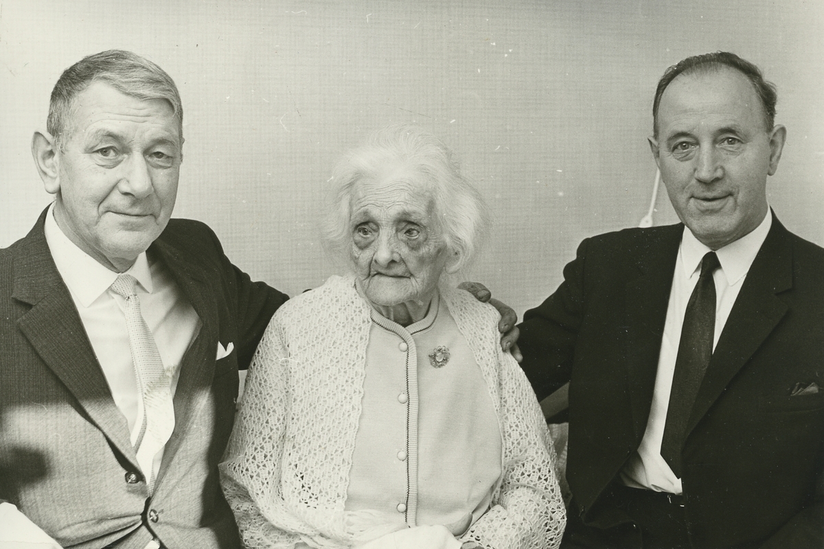 Gustavsgården. Anna Stein tillsammans med två gratulanter firas på sin hundraårsdag den 14 januari 1967.
Personer: Anna Stein och två okända herrar.
