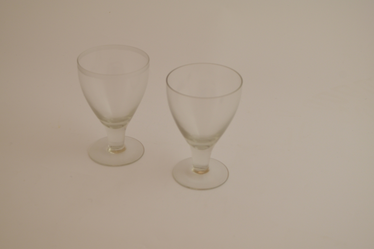 To glass. Rund fotplate, stett uten dekor. Et glass har klokke uten dekor, og et glass har dekor av en stripe nedenfor munningssranden.