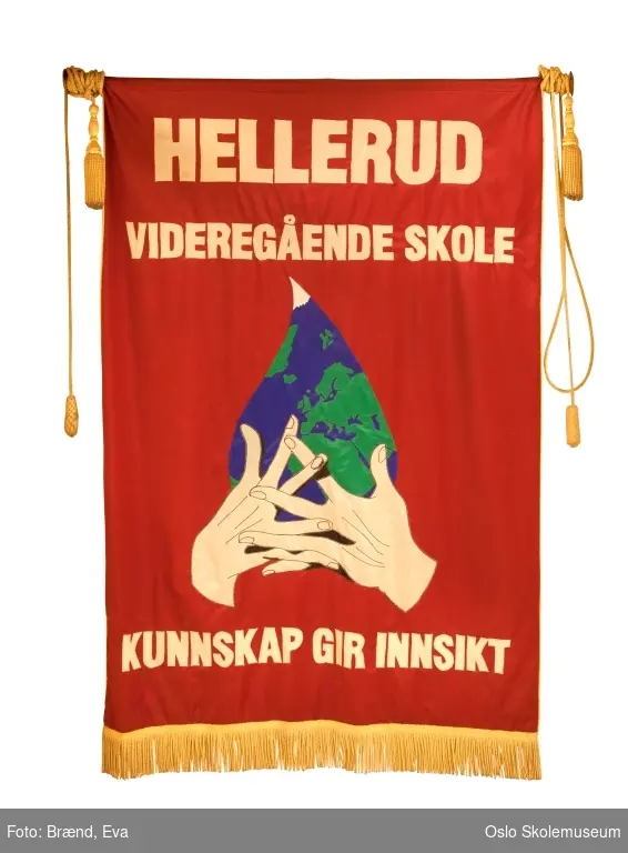 To hender som holder en dråpe der jordkloden gjenspeiles på rød bakgrunn. Motivet er hentet fra skulpturen "Dråpen av Erling Ur Jonsson som står ved skolens administrasjonsbygg.