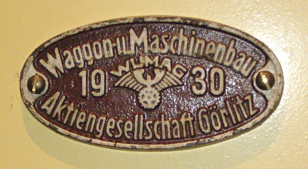 Oval och brunmålad vagntillverkarskylt av järn.
Text: "Waggon u Maschinenbau Aktiengesellschaft Görlitz 1930".