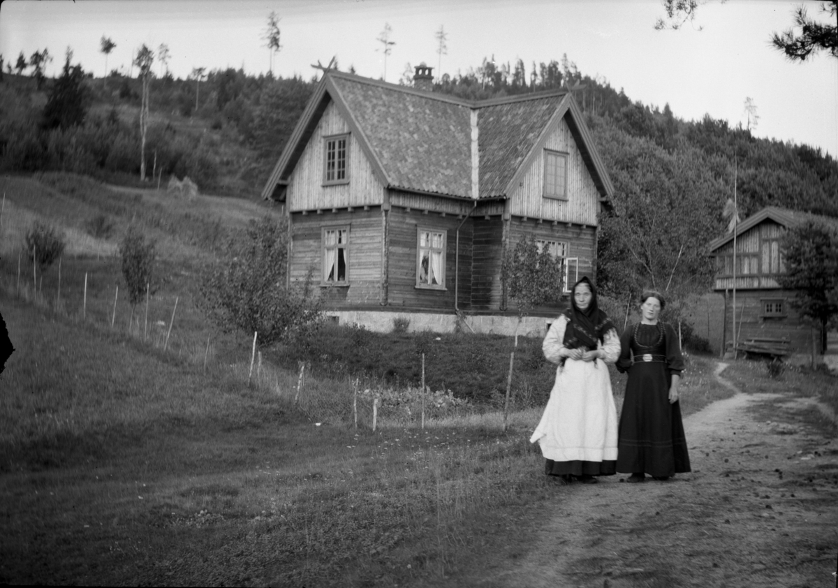 Rikard Berges fotoarkiv. To kvinner fotografert foran hus, gårdstun.