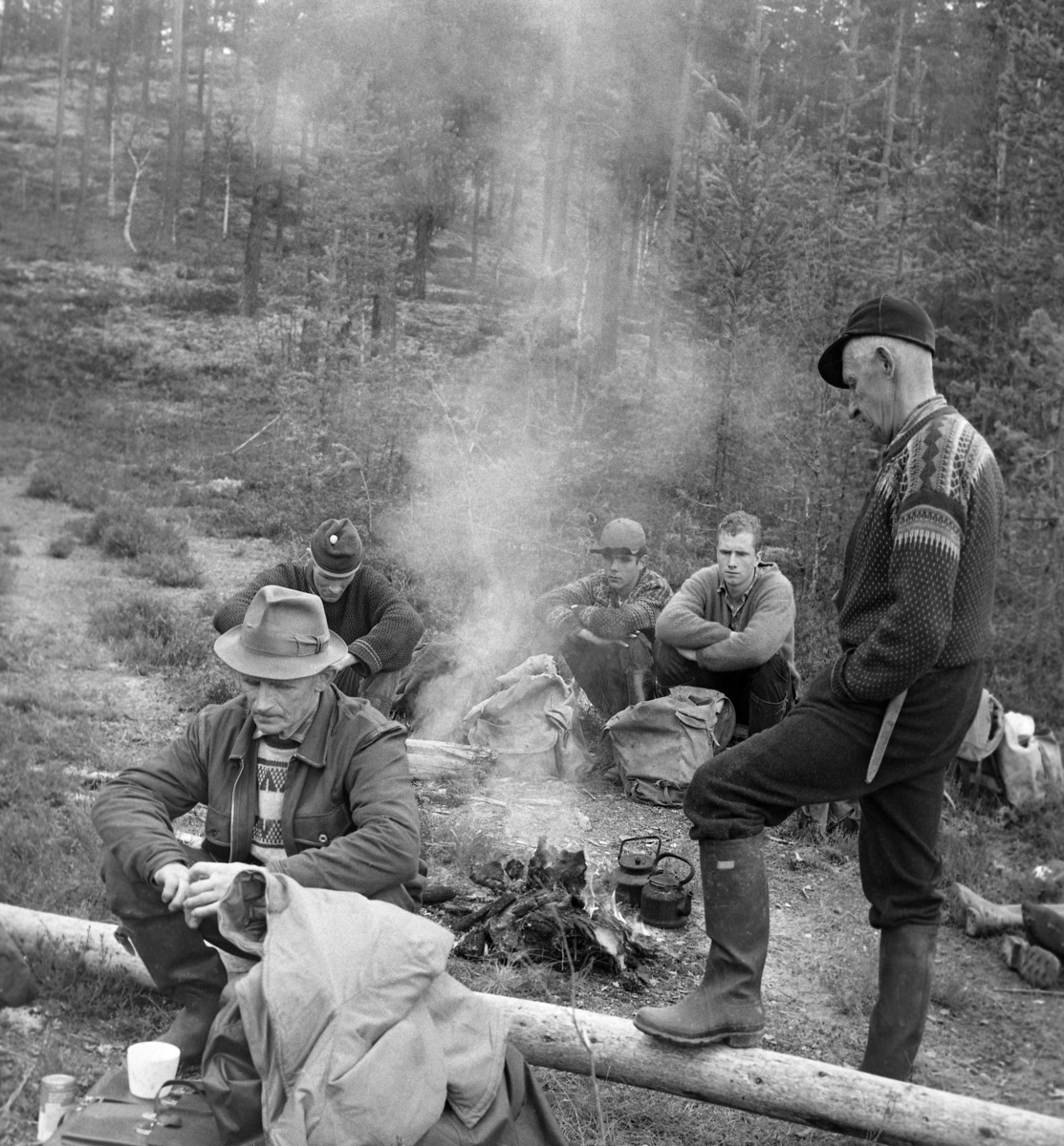 Seks tømmerfløtere kviler på en elvebrink ved Julussa i Elverum i Hedmark våren 1969.  Kvileplassen er en lysning i et landskap med furuskog, der karene har gjort opp et lite bål.  To sotete kaffekjeler ved siden av bålet tyder på at de har nytt litt varmt drikke.  En foreløpig uidentifisert kar satt på en tømmerstokk i forgrunnen, mens tre noe yngrer karer satt på bakken på den andre sida av bålet.  Dette var Kjell Arne Langdalen (med topplue), Finn Sletengen (med skjoldlue), Simen Bergerengen (barhodet).  Ved den nevnte stokken, til høyre i bildet, sto basen for dette fløterlaget, Asbjørn Langdalen fra Nordskogbygda.  Han var kledd i mørke vadmelsbukser og mønstret strikkejakke, hadde gummistøvler på beina og skjoldlue på hodet.  Flere av karene hadde tydeligvis ryggsekker av grått lerretsstoff med niste og kanskje noen tørre klær.  Mannen som sitter til venstre i forgrunnen ser ut til å ha med seg ei kontorveske av lær, som han bruker som underlag for det kvite kaffekruset sitt. 

1969 var siste fløtingssesong i Julussa.  Det ble fløtet 40 580 stokker med et samlet kubikkmetervolum på 4 277.  Dette var bare cirka 15 prosent av det fløtingsvolumet vassdraget hadde hatt i de første åra etter 2. verdenskrig.