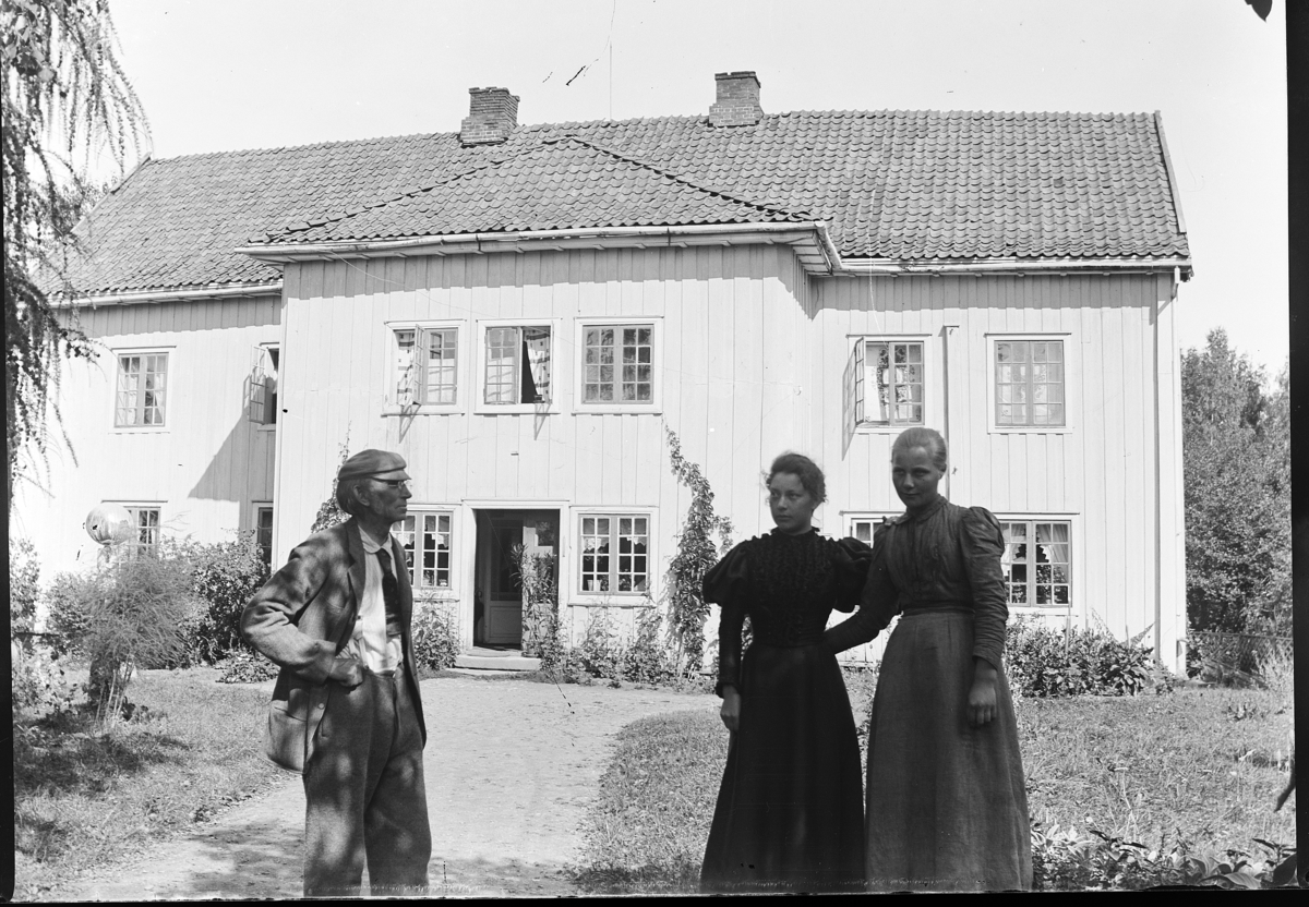 Gruppe 3, mann, to kvinner foran bygning, Østre Dælin ?,  Stange.