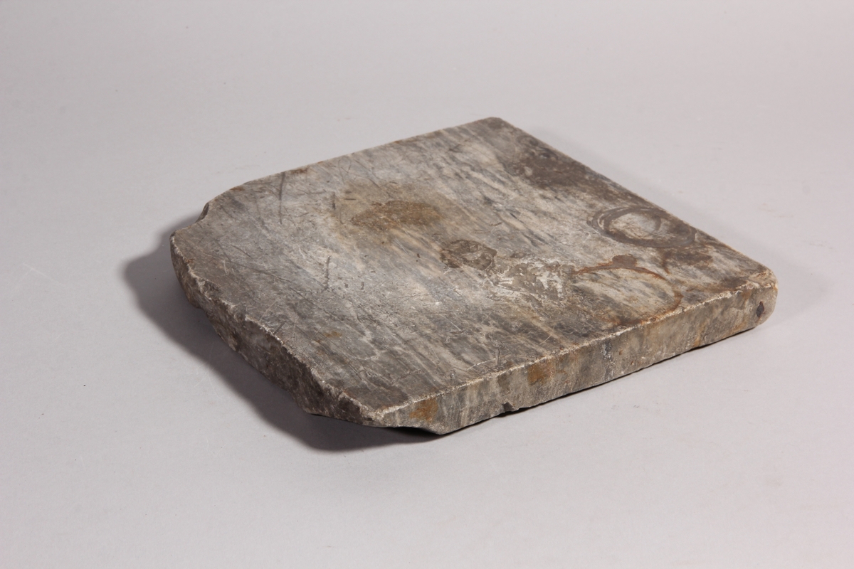 Platta av marmor till rivsten med tillhörande löpare av röd porfyr. Plattan med slät ovansida och huggen undersida.