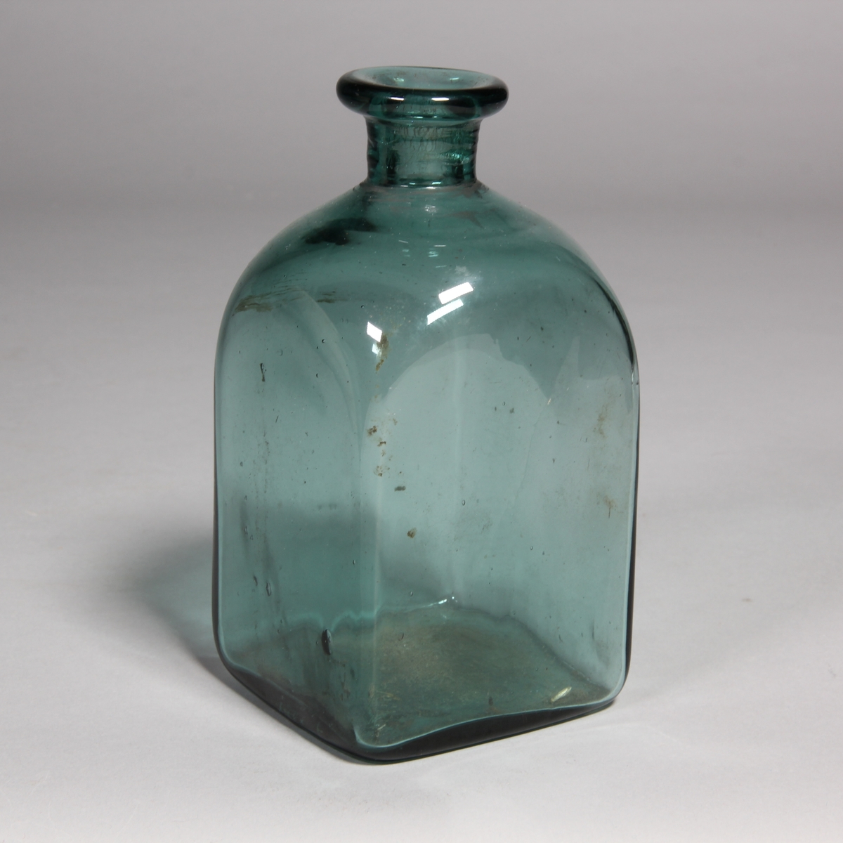 Flaska av grönt glas, kvadratisk med utvikt mynning.