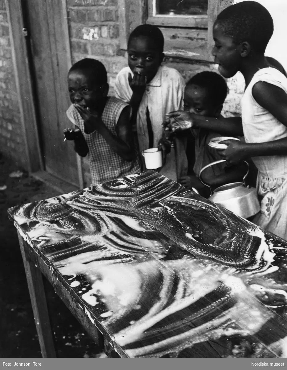 Biståndsverksamhet, Kongo. Barn får mjölk, som de skrapar upp från ett bord.