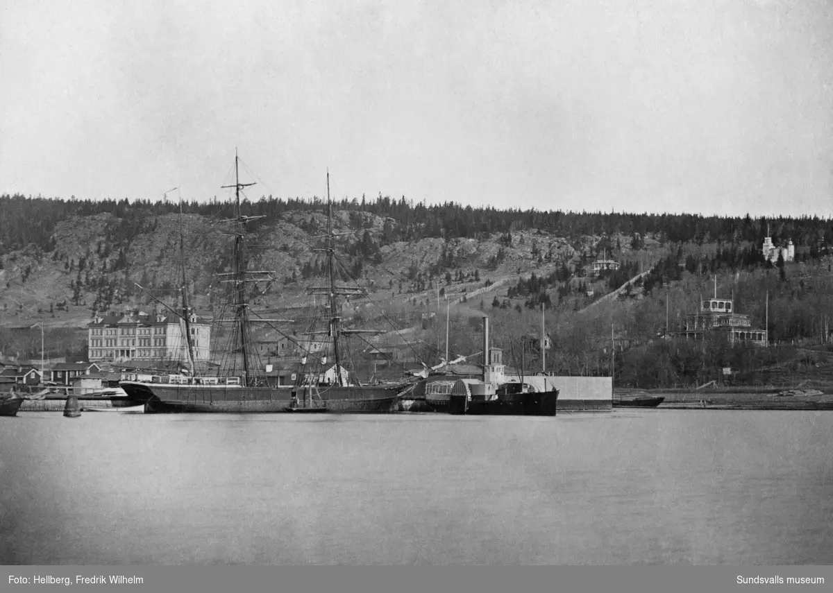 Hamnen med ett segelfartyg och hjulångaren "Swartvik". På bilden till vänster Sundsvalls lasarett, i mitten på bilden bakom hjulångaren syns ett torn vilket hör till kallbadhuset och till höger på bild syns Tivoli. Bildtext i allbum "Hamnen, Lasarettet, badhuset och Tivoli i bakgrunden."