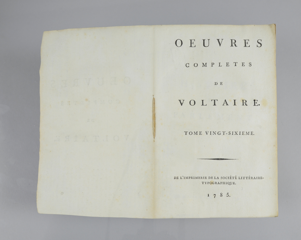 Bok, pappband,"Oeuvres completes de Voltaire", del 26 "Histoire du parlement de Paris ", tryckt 1785.
Pärmen klädd med gråblått papper, på pärmarnas insidor klistrade sior ur annan bok. Med skurna snitt. På ryggen klistrad pappersetikett med tryckt text samt volymens nummer. Ryggen blekt.