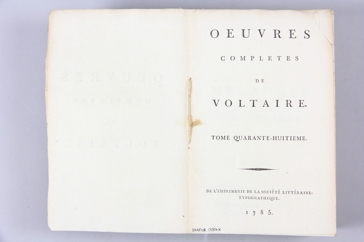 Bok, pappband,"Oeuvres complètes de Voltaire." del 48, tryckt 1785.
Pärm av gråblått papper, skurna snitt. På ryggen pappersetikett med tryckt text med volymens namn och nummer. Ryggen blekt.