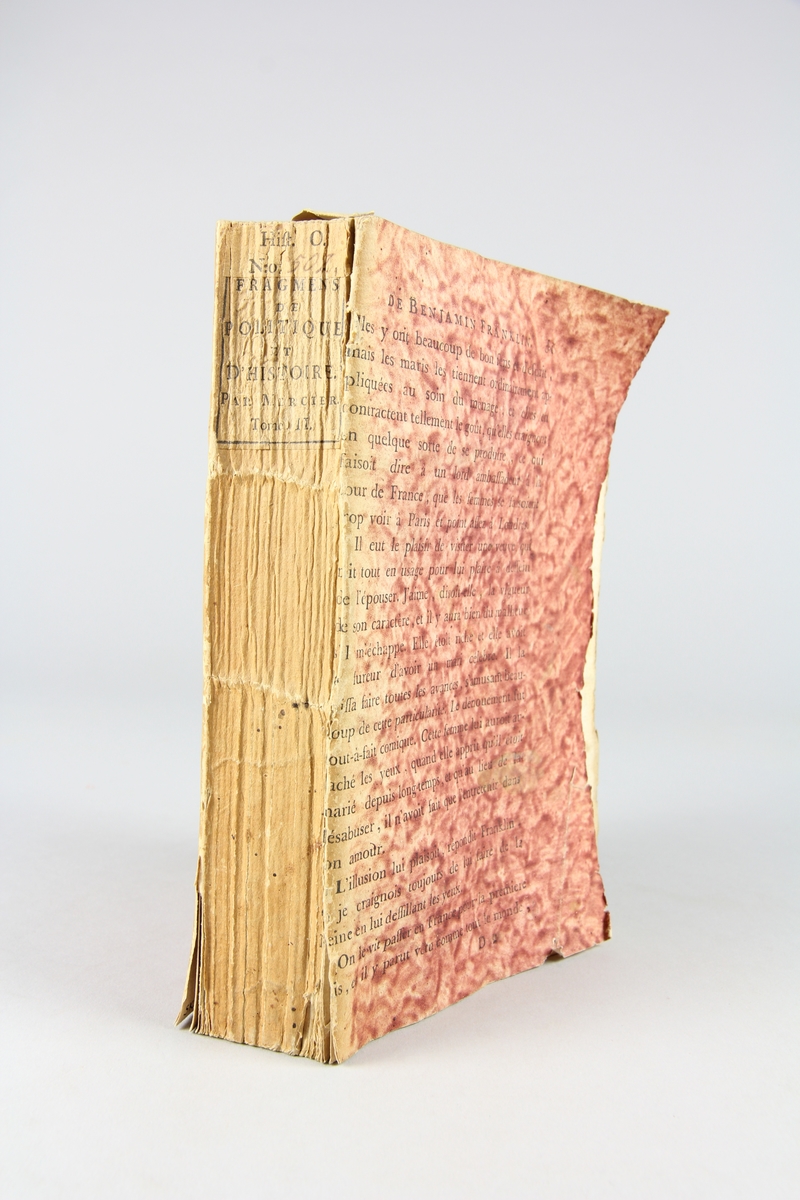 Bok, "Fragments de politique et d´histoire", del 2, tryckt 1792  i Paris. Pärmar av rödmönstrat papper med tryckt text ur annan bok. Skuret snitt. På ryggen tryckt etikett med volymens titel och samlingsnummer.