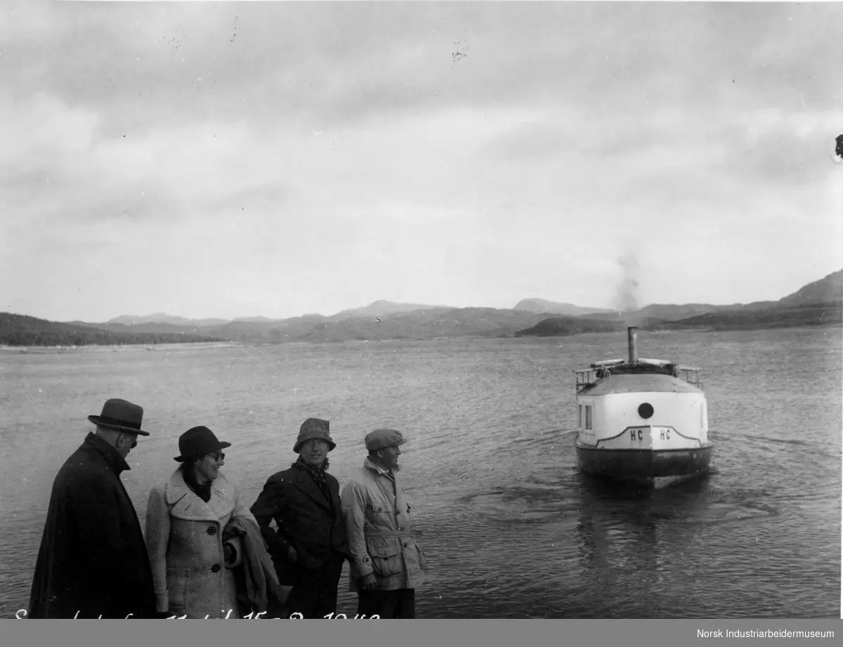 Båten "HC " på Møsvann. I vannkanten står det mennesker. Anledningen er tur til Sundet.