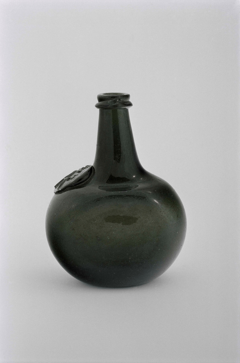 Flaska av grönt glas, oval med tillplattade sidor, lång hals med droppskydd. Sigill med krona samt " 17 A 51 ".