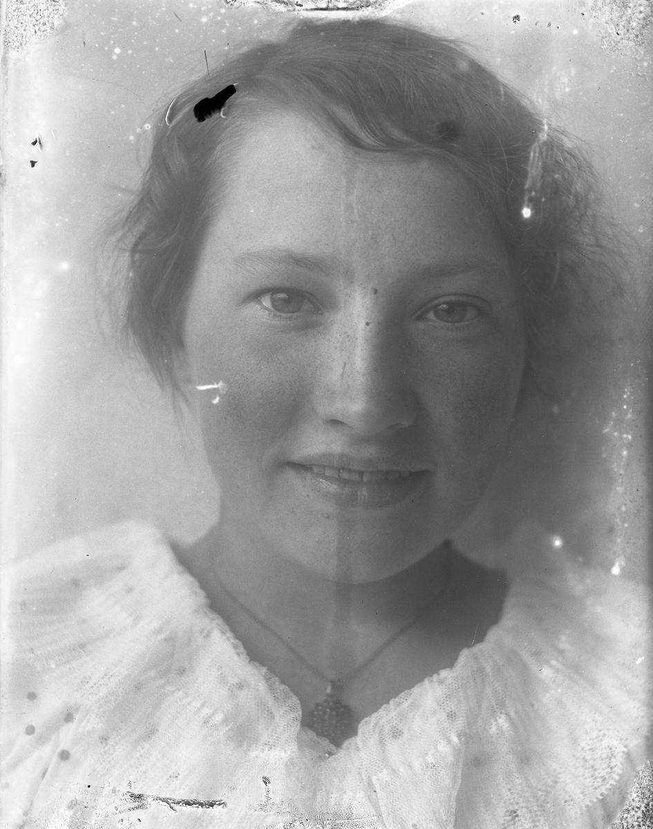 Porträtt av Annie Hultén i vitt med ett halsband, troligen med granater, om halsen.