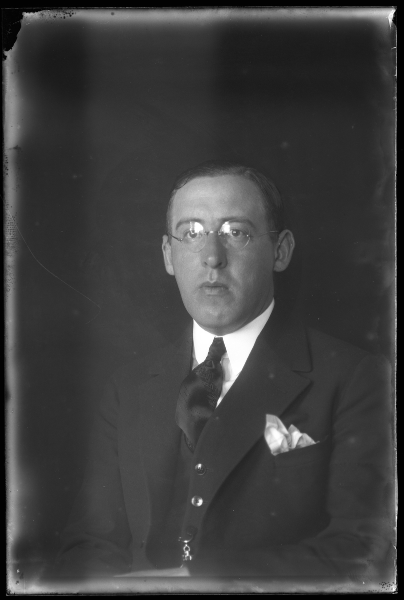 Porträtt av Thure Wigren i tredelad mörk kostym, vit skjorta, slips och glasögon.