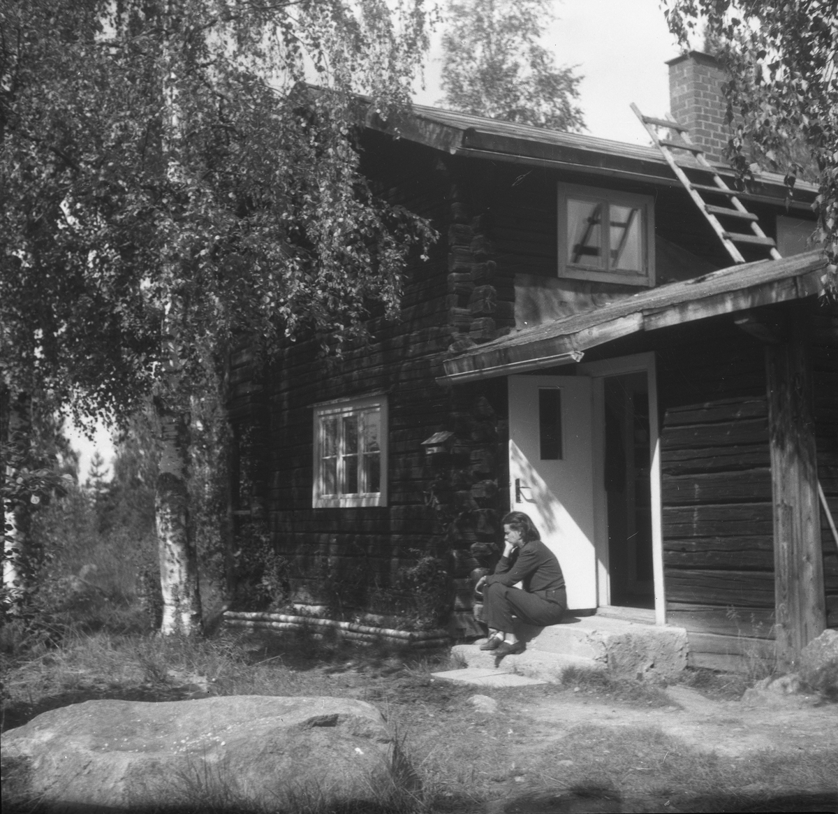 Ensam flicka framför hus, 1930-tal, kanske Sörberga. Edith Perssons atelje'.