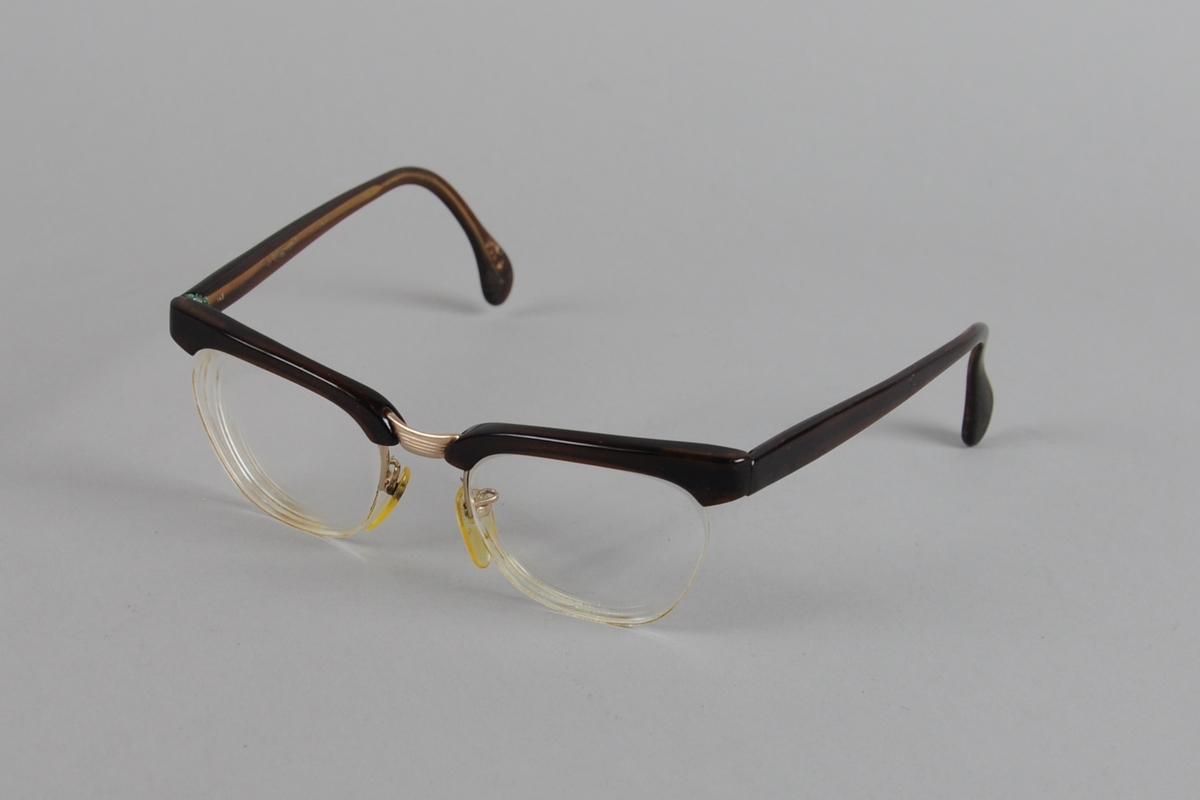 Briller med brilleinnfatning kun på oversiden av brilleglassene. Innfatningen er av metall med mørkebrunt plastbelegg.