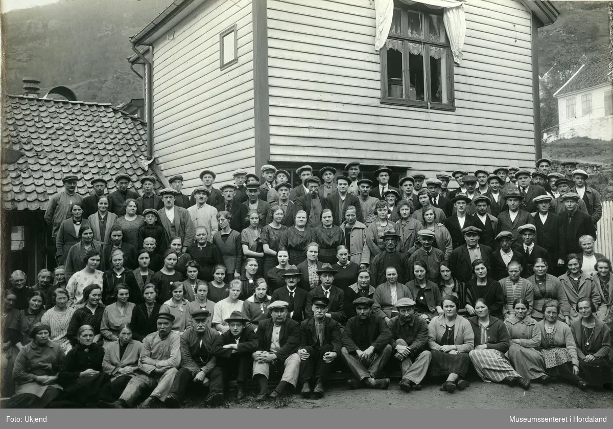 Gruppeportrett av arbeidarane ved Salhus Tricotagefabrik i 1926. I bakgrunnen kan ein sjå den gamle kontorbygningen til fabrikken.